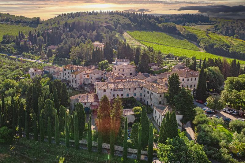 View of an historic village and winery amidst rolling hills and vineyards in the Chianti region.