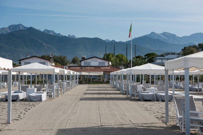 Gilda Beach Club, a luxury resort located in Forte dei Marmi, Tuscany, Italy. The club features typical beach chic decor with white-washed walls, wood furniture, and signature white gazebos lining the sand.